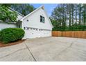 Spacious three-car garage with white doors and a large driveway and a wooden fence at 6655 Manchester Pl, Cumming, GA 30040