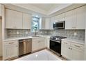 Modern kitchen with white cabinets, stainless steel appliances, and a stylish backsplash at 5023 Rockborough Trl, Norcross, GA 30071