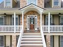 Charming front entrance showcasing a wooden door, stone accents, and a welcoming porch with decorative details at 92 River Walk Pkwy, Euharlee, GA 30145
