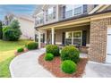 Inviting covered porch with neatly trimmed shrubs and a walkway leading to the front door at 4560 Buckskin Way, Douglasville, GA 30135