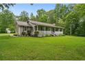 Single-story home featuring a welcoming front porch, metal roof, and lush green lawn at 1267 Austin Bridge Rd, Douglasville, GA 30134