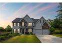 Traditional two-story home with stone accents, attached two car garage, well-manicured lawn, and inviting curb appeal at sunset at 121 Bradshaw Park Dr, Woodstock, GA 30188