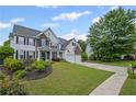 Landscaped front yard featuring a well-manicured lawn, vibrant flowers, and a charming two-story home with a covered front porch at 121 Bradshaw Park Dr, Woodstock, GA 30188