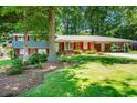 Well-maintained home with lush green lawn, mature trees, brick accents, and charming red shutters at 5152 Suggs St, Powder Springs, GA 30127
