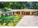 Inviting home featuring a well-manicured lawn, mature landscaping, and a convenient covered carport at 5152 Suggs St, Powder Springs, GA 30127