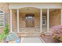 Inviting covered front porch with stone pillars and a beautifully crafted wooden door at 2430 Hemrick Rd, Cumming, GA 30041