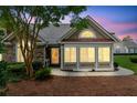 Charming home exterior at sunset featuring stone accents, large windows, and lush landscaping at 6107 Malloway Ct # B-6107, Cumming, GA 30041