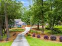 A long driveway leads to a charming blue two-story home nestled in a lush, wooded landscape at 7250 Hunters Branch Dr, Atlanta, GA 30328