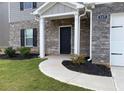 Inviting front exterior features brick accents, well-manicured lawn, covered entryway, and walkway to the front door at 117 Oliver Dr, Locust Grove, GA 30248