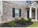 This home features brick accents, dark shutters, a well-manicured lawn, and a covered entryway at 117 Oliver Dr, Locust Grove, GA 30248