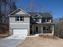 Two-story home featuring a covered porch, attached garage, and neutral siding on a sunny day at 250 Shawnee Trl, Dallas, GA 30157