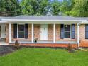 Welcoming front porch with brick columns, black shutters, and a freshly painted white front door at 414 Landers Sw Dr, Mableton, GA 30126