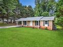 Brick home with a neatly maintained lawn, a cozy covered porch, and an attached carport at 414 Landers Sw Dr, Mableton, GA 30126