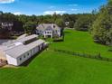 Picturesque aerial view of house and large barn facility set amongst rolling green fields at 206 Savanna Estates Ct, Canton, GA 30115