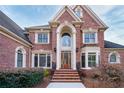 Striking two-story brick home featuring a grand arched entryway and meticulously maintained landscaping at 2760 Sugarloaf Club Dr, Duluth, GA 30097