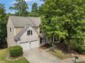 Aerial view of a two-story brick home with a two-car garage, spacious driveway, and mature trees at 5828 Paliser Trce, Sugar Hill, GA 30518