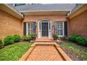 Inviting front entrance with a brick pathway, dark door, black shutters, and potted flowers at 3030 Spalding Dr, Sandy Springs, GA 30350