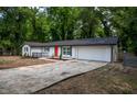 Low angle of a bright white home with dark shutters, orange door, and a large driveway with an attached two-car garage at 5640 Redan Cir, Stone Mountain, GA 30088