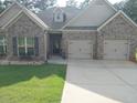 Charming brick home featuring a two-car garage and well-manicured lawn at 1128 Carillon Dr, Conyers, GA 30013