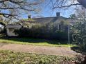 A cozy, single-story home with a classic design and partially obscured by lush greenery at 5121 Newark Ave, Clarkdale, GA 30111