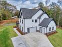 Beautiful home featuring modern garage doors, white siding, and meticulous landscaping at 1387 Mineral Springs Rd, Hoschton, GA 30548