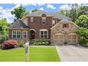 Charming two-story brick home featuring a manicured lawn, stone accents, and a two-car garage at 4896 Locklear Way, Marietta, GA 30066