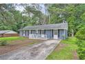View of a well-maintained single-story home with a gray brick exterior and a concrete driveway leading up to it at 62 Sunny Ln, Villa Rica, GA 30180