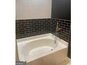 Bathroom featuring a soaking tub with black tiled walls and gold fixtures at 870 Mayson Turner Nw Rd # 1102, Atlanta, GA 30314