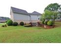 View of home exterior with large grassy backyard, brick retaining wall, and mature trees at 168 Harmony Grove Rd, Lilburn, GA 30047