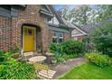 Inviting yellow front door of a brick home, enhanced by a cozy seating area and vibrant landscaping at 451 S Columbia Dr, Decatur, GA 30030