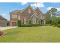 Elegant brick and stone home with a lush lawn, manicured shrubs, and a welcoming two-car garage at 2450 Weber Heights Way, Buford, GA 30519