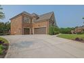 Spacious three-car garage with a long driveway, surrounded by well-maintained landscaping and lush greenery at 2450 Weber Heights Way, Buford, GA 30519