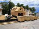View of a house under construction with exposed framing alongside several large waste disposal containers at 727 Crest Line Trl, Powder Springs, GA 30127