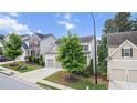 Street view of the home featuring a two-car garage, manicured lawn, and lush landscaping at 2013 Chesley Dr, Austell, GA 30106