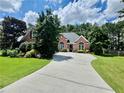 Beautiful red brick home with a lush green lawn, a winding driveway, and mature trees at 1902 Commons View Cir, Snellville, GA 30078