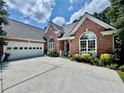 Charming red brick home with a two car garage, arched windows, and a concrete driveway at 1902 Commons View Cir, Snellville, GA 30078