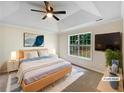 Staged main bedroom features a tray ceiling, a ceiling fan, and a large window at 1792 Portwest Way, Hampton, GA 30228