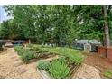 Lush backyard featuring raised garden beds, gravel pathways, and a charming storage shed at 2904 Masonwood Nw Dr, Kennesaw, GA 30152