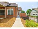 View of a well-maintained brick house featuring manicured landscaping, a concrete walkway and privacy fence at 4347 Lanier Ridge Walk # 1501, Cumming, GA 30041