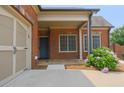 A welcoming brick front entrance features a covered porch, blooming hydrangeas, and convenient garage access at 4347 Lanier Ridge Walk # 1501, Cumming, GA 30041