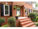 Close-up of the brick entryway, decorative plants, and a classic white front door with wreath at 4497 Windsor Oaks Dr, Marietta, GA 30066