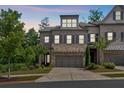 Exterior of the townhome at dusk shows stone accents, two-car garage, and pretty landscaping at 1099 Heyward Way, Alpharetta, GA 30009