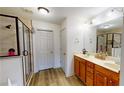 Well-lit bathroom featuring double vanity, wood cabinets, walk-in shower with glass door and wood-look floors at 3325 Castleberry Village Cir, Cumming, GA 30040