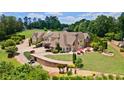 A large home with a stone retaining wall, patio with red umbrellas, and lush landscaping at 2220 Peachtree Rd, Cumming, GA 30041