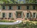 Inviting brick home with green shutters, a 'welcome' sign and neatly manicured landscaping at 2982 Huntshire Pl, Atlanta, GA 30340