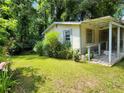 Quaint single story house on a large lawn with overgrown landscaping and a partially covered porch on its side at 53 Elm St, Hampton, GA 30228