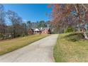 Driveway leading to a brick home with a covered porch, surrounded by mature trees and landscaping at 5826 Little Mountain Dr, Ellenwood, GA 30294