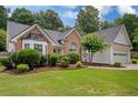 Charming single-story home features a brick facade, well-manicured lawn, and mature trees at 1865 Morgans Run Trl, Buford, GA 30519