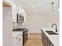 Modern white and dark gray kitchen featuring an island, stainless steel appliances, and pendant lighting at 105 Priestwood Ln, Acworth, GA 30102