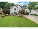 Beautiful two-story home featuring a lush lawn, professional landscaping, and a charming, painted white brick facade at 340 Chandler Ct, Sugar Hill, GA 30518